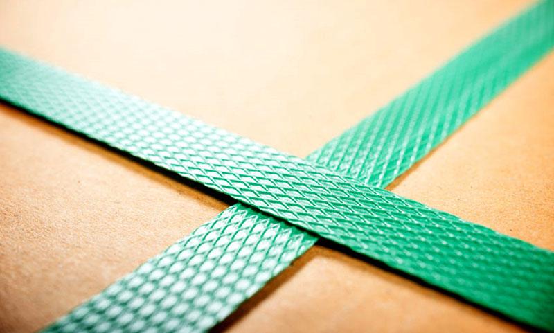 Groene plastic omsnoeringsband rond een kartonnen doos