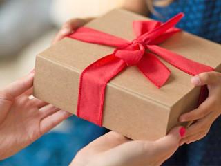 Overhandiging van een cadeau ingepakt in een bruine doos omwikkeld met een rode strik
