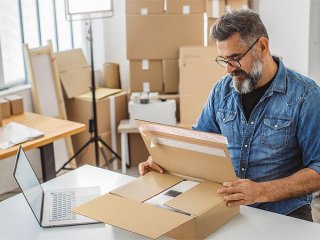 Man staat aan inpaktafel en bereidt een doos voor op een e-commerce verzending