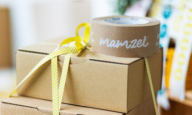 Gestapelde dozen met erboven een bedrukte tape met het logo van Mamzel