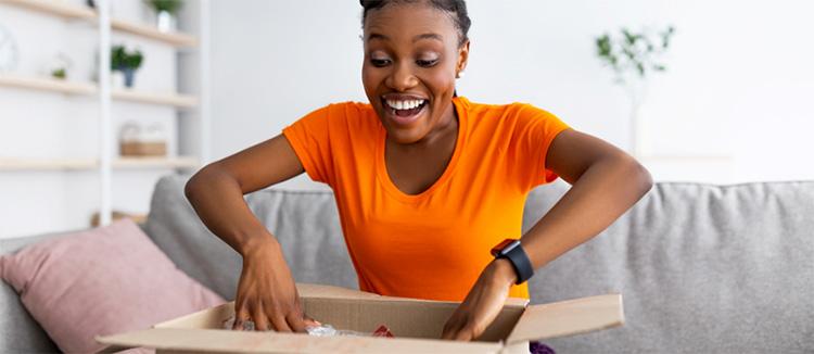 Une femme ouvre une boîte monomatériau en souriant.