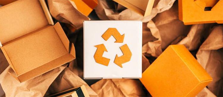 Stapels kartonnen en papieren monoverpakkingen met recyclage symbool in het midden