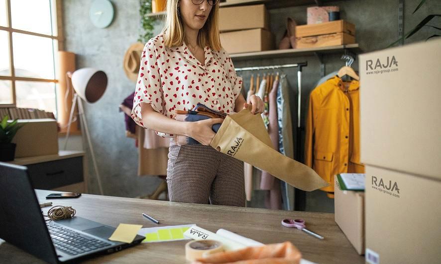 Une femme met un vêtement dans un sac d'expédition en papier de RAJA