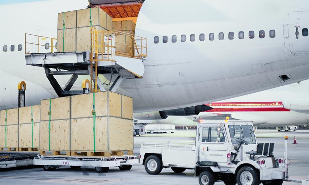Des caisses de transport en bois sont chargées dans un avion
