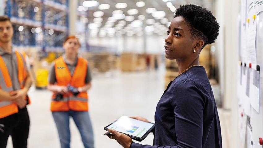 Une responsable logistique femme accompagne les nouveaux employés dans un entrepôt humain