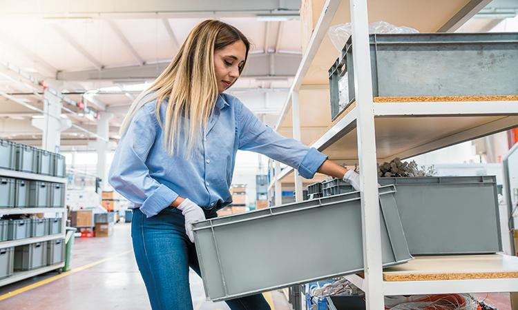 Vrouw plaatst stapelbak in een magazijnrek